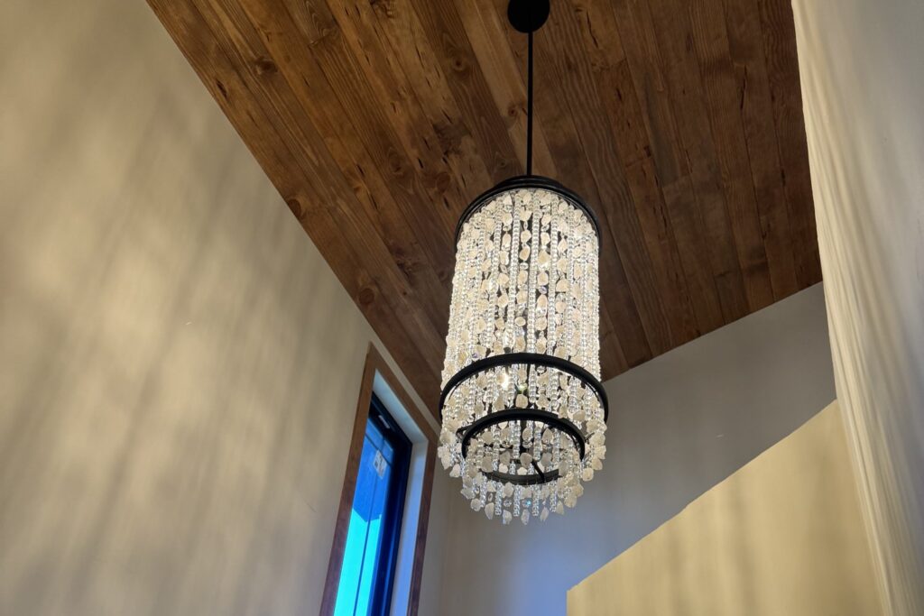 Crystal chandelier hanging from a wood ceiling in a two-story stairwell