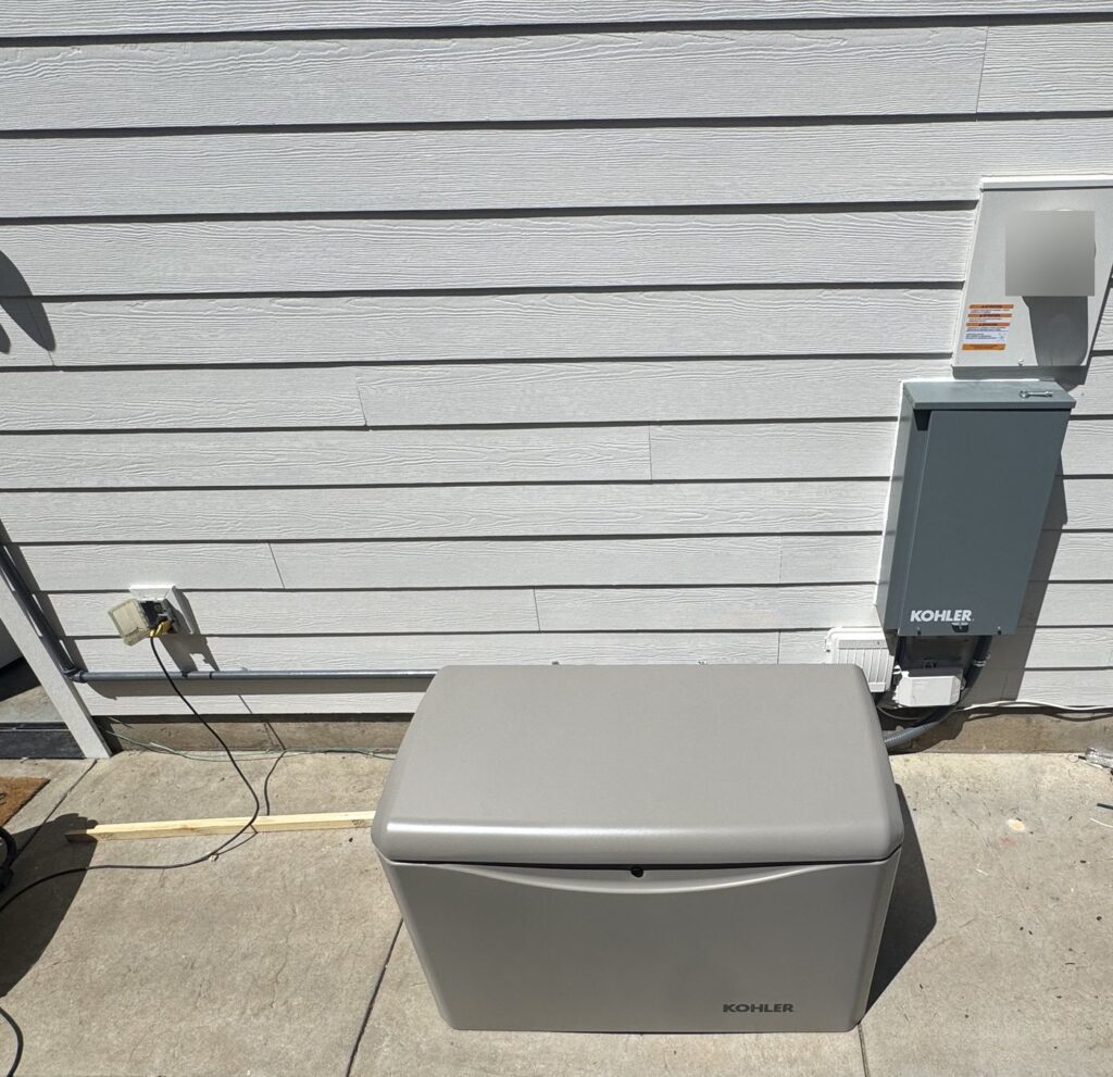 Kohler home standby generator on a paver patio next to its transfer switch