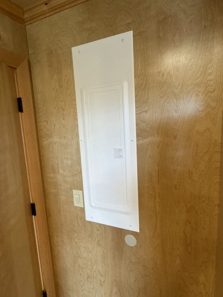 New Leviton breaker panel with the door closed, flush-mounted in a wood wall
