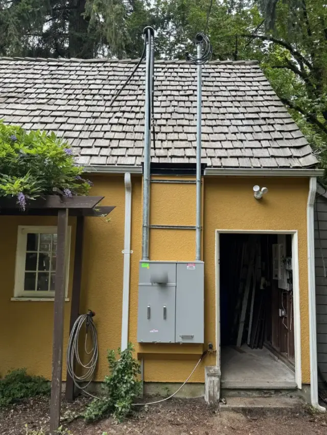 New meter main service with two service masts on a yellow stucco garage