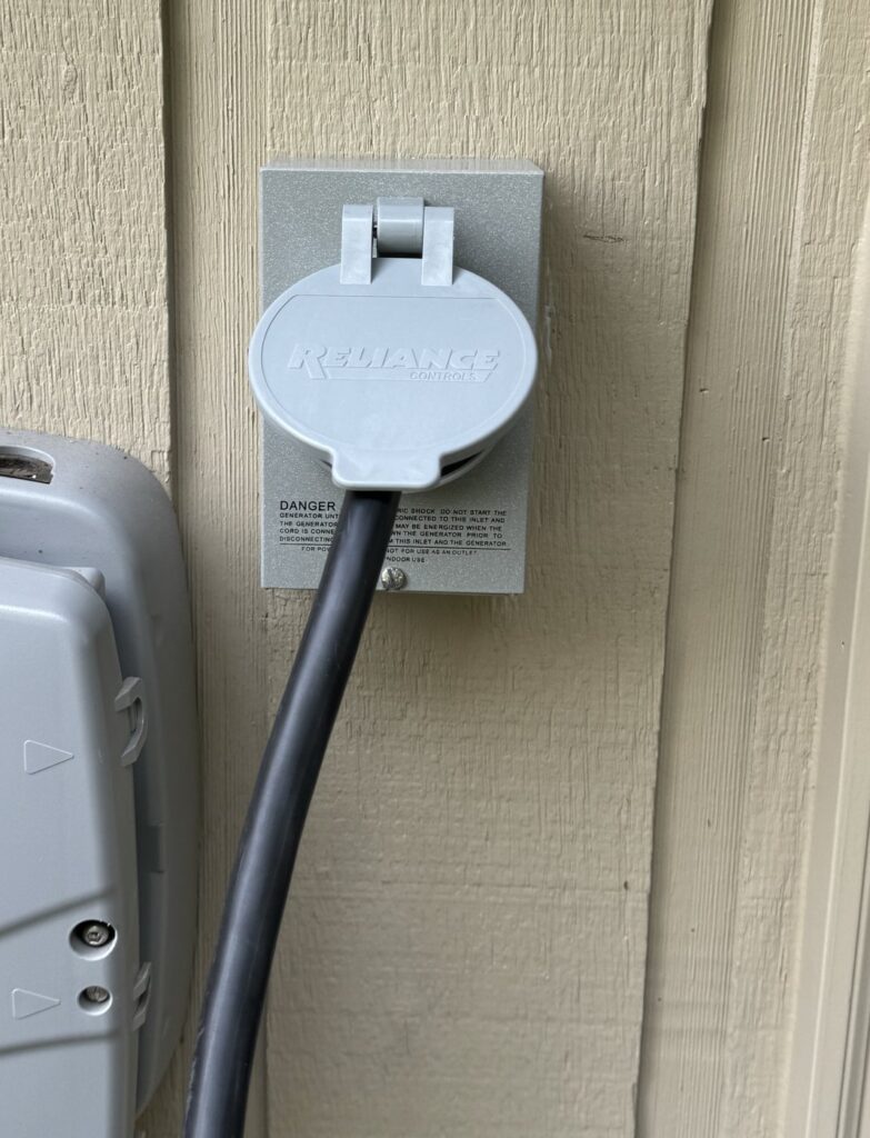 Reliance outdoor power inlet with a portable generator cord plugged in